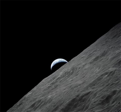 View of Earth rising above the Moon's horizon as seen from lunar orbit, showing the rugged surface of the Moon in the foreground and a partially illuminated Earth in the background