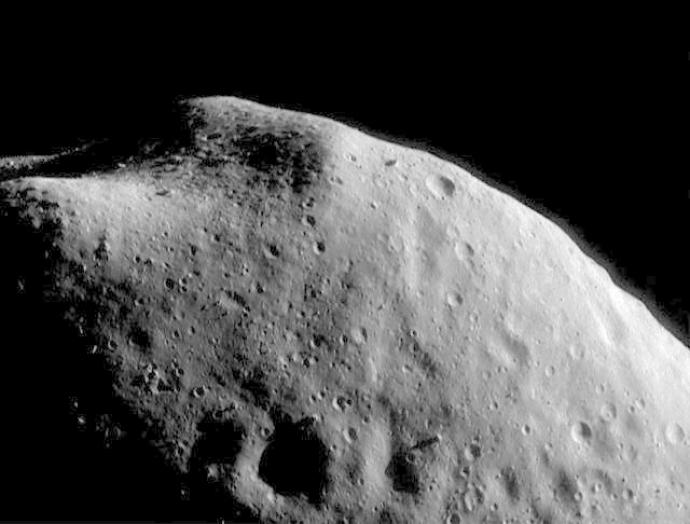 A close view of Eros asteroid showing a grey and cratered surface.