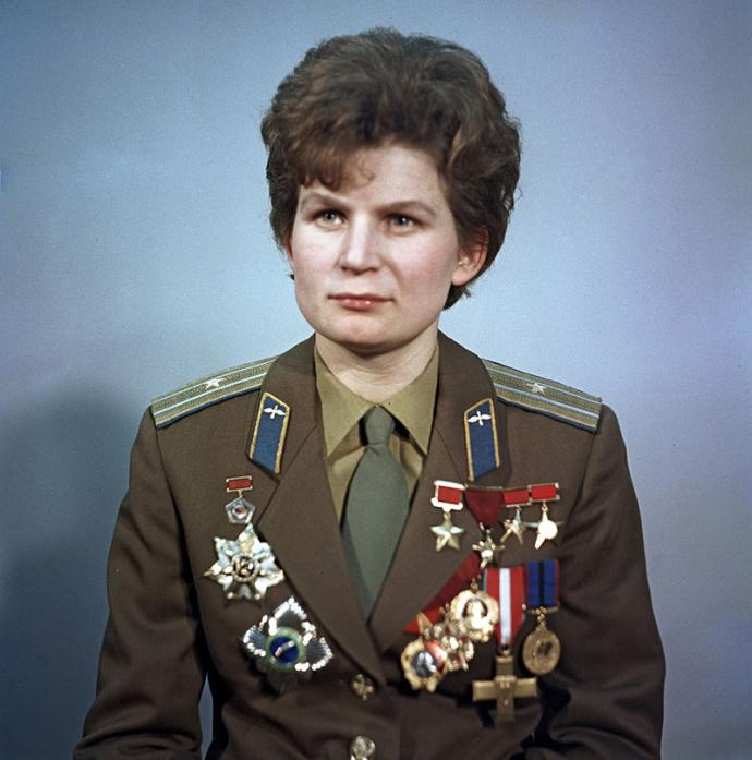 A portrait of Valentina Tereshkova, the first woman to fly in space, wearing a military uniform adorned with several medals and honors. She appears calm and composed, symbolizing her historic achievements as a Soviet cosmonaut