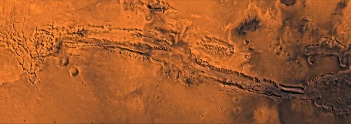 Panoramic view of Mars's surface showing Valles Marineris, a deep canyon system stretching across the red planet with rugged terrain and visible impact craters